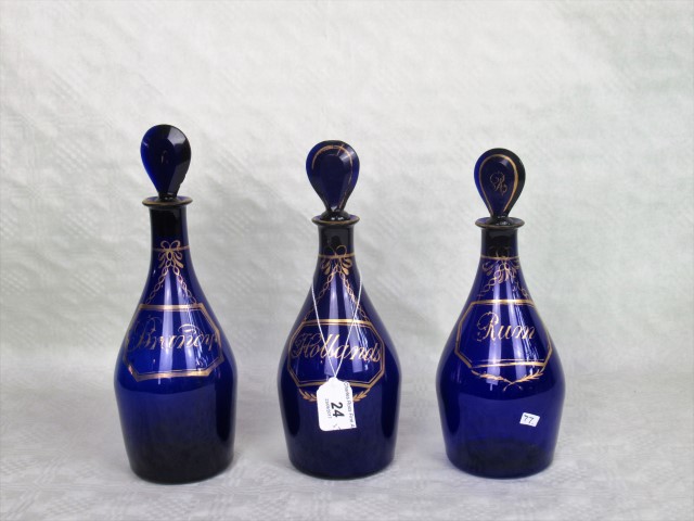 A set of three 19th century blue glass decanters and stoppers, each having gilt decoration,