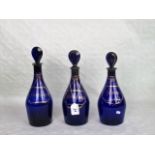 A set of three 19th century blue glass decanters and stoppers, each having gilt decoration,