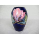 A Moorcroft vase in the Hibiscus pattern, having tube-lined decoration on a deep blue ground,