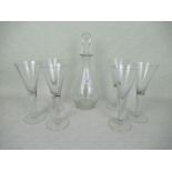 A clear glass decanter and stopper, together with a set of six tall wine glasses.