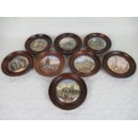 A collection of eight Pratt Ware pot lids, each in a turned wooden frame,