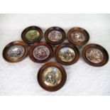 A collection of eight Pratt Ware pot lids, each in a turned wooden frame,