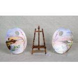 Two small ceramic artist's palettes, each decorated with a river landscape,