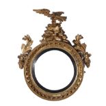 Regency carved giltwood bull's-eye mirror first quarter 19th century, eagle pediment and leaf