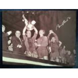 Bobby Charlton signed 24 x 18 inch canvas print holding the European Cup. Mounted on wood frame.