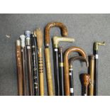 A collection of thirteen walking canes to include a clarinet cane, two drinker's canes with glass