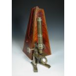 A mid 19th century brass monocular microscope, on a Y shaped foot, contained in a figured