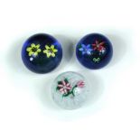 Three John Deacon glass paperweights, comprising pink flowers on a latticino ground and two floral