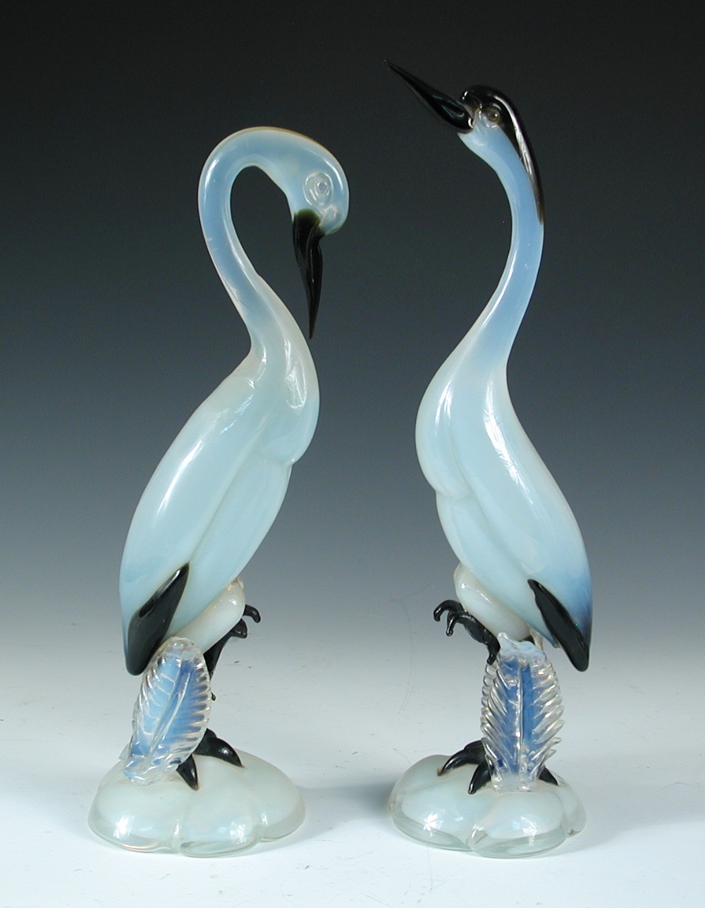 A pair of mid-20th century Murano glass cranes, the opalescent and black glass models each