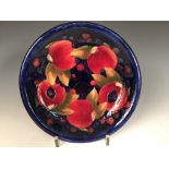 A Moorcroft Pomegranate pattern plate, decorated with both open and closed fruit to a blue ground,