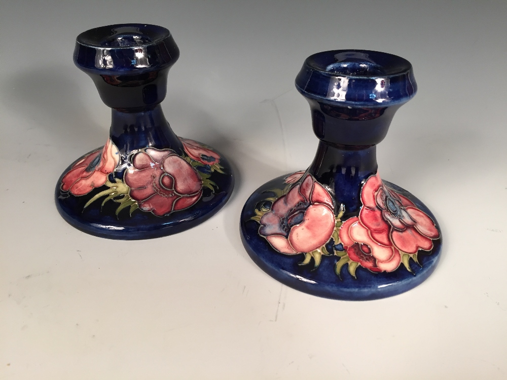 A pair of Moorcroft Anenome pattern dwarf candlesticks, each decorated to a deep blue ground,