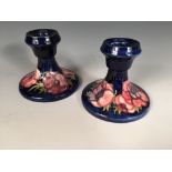 A pair of Moorcroft Anenome pattern dwarf candlesticks, each decorated to a deep blue ground,