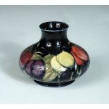 A small Moorcroft Wisteria pattern vase, the squat form decorated to a deep blue ground, painted and