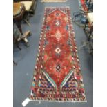 A red ground tribal rug 294cm x 90cm