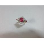 A treated ruby and diamond ring, the central cluster with an oval cut ruby in a border of diamonds