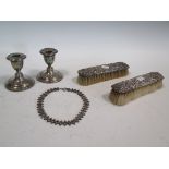 A pair of silver dwarf candlesticks, silver backed hairbrushes a/f, and a bracelet (5)