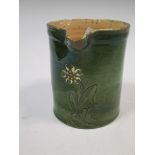 A Farnham pottery green glazed jug, the front decorated with a floral spray, 17cm high