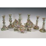 Three pairs of floral encrusted candlesticks; a pair of floral encrusted and painted rustic