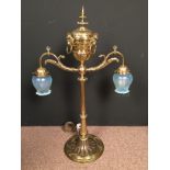 A brass twin branch table lamp, the pierced urn form top with lion mask mounts and ring handles