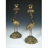 A pair of gilt bronze candlesticks modelled as cranes, each with a crown around the neck, their