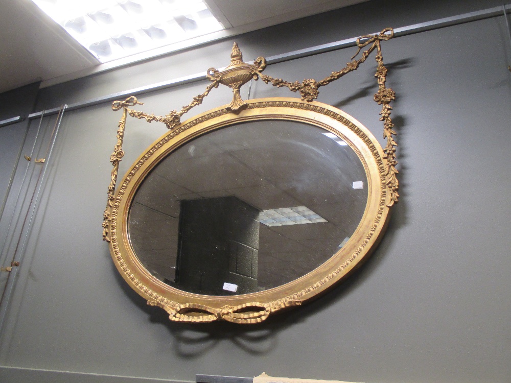 A 19th century oval gilt framed wall mirror with urn and swag decoration