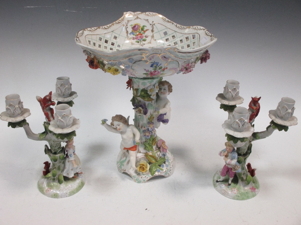 A Dresden floral encrusted porcelain fruit stand with amorini and a pair of similar three-light