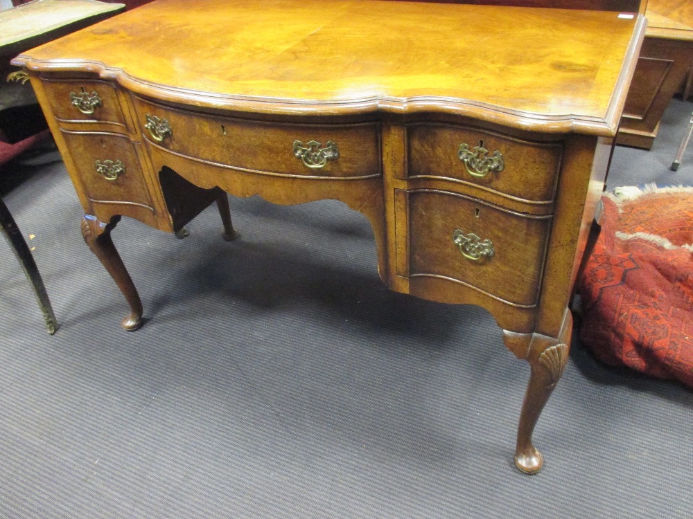 An old reproduction walnut dressing table fitted with one central and two deep side drawers, on