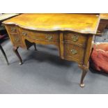 An old reproduction walnut dressing table fitted with one central and two deep side drawers, on