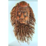 A bamboo root wood mask, the rootlets forming hair and beard to frame the face of a balding man,