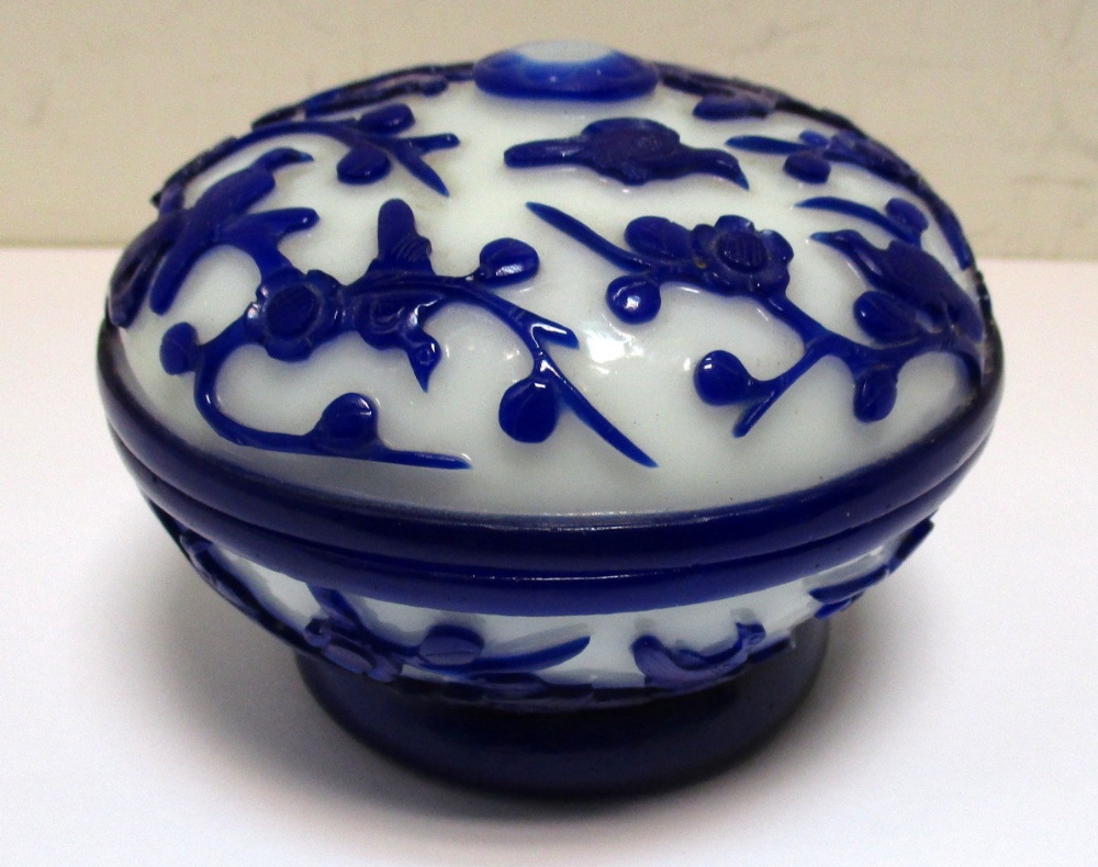 A Pekin blue overlay milk glass box and cover, the footed bun shape carved in relief with birds