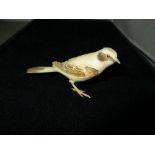 An early 20th century ivory carving of a bird, possibly a Great GreyShrike, the bird's back tinted