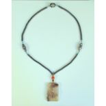 An agate pendant to a jet black bead necklace, the grey rectangular stone with smokey brown