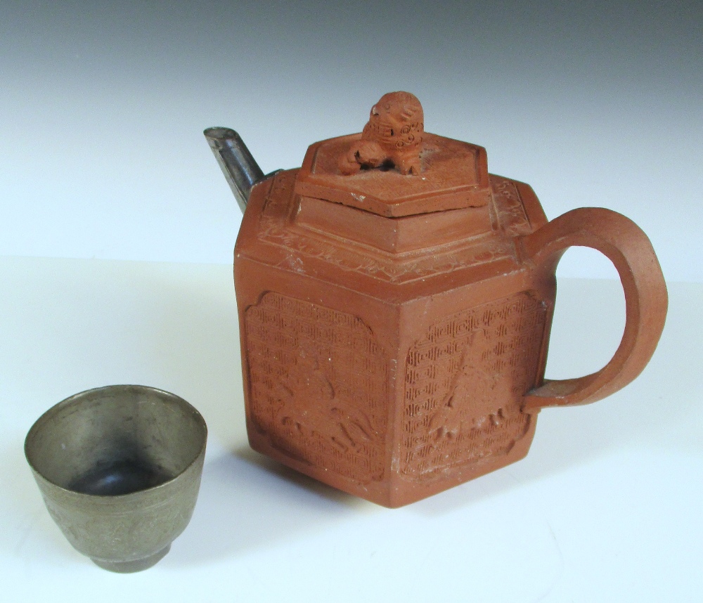 An 18th century Yixing tea pot together with a pewter tea bowl, the hexagonal sides of the pot