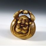 A late 19th/early 20th century marine ivory netsuke stained and carved as Hotei wrapped in his own