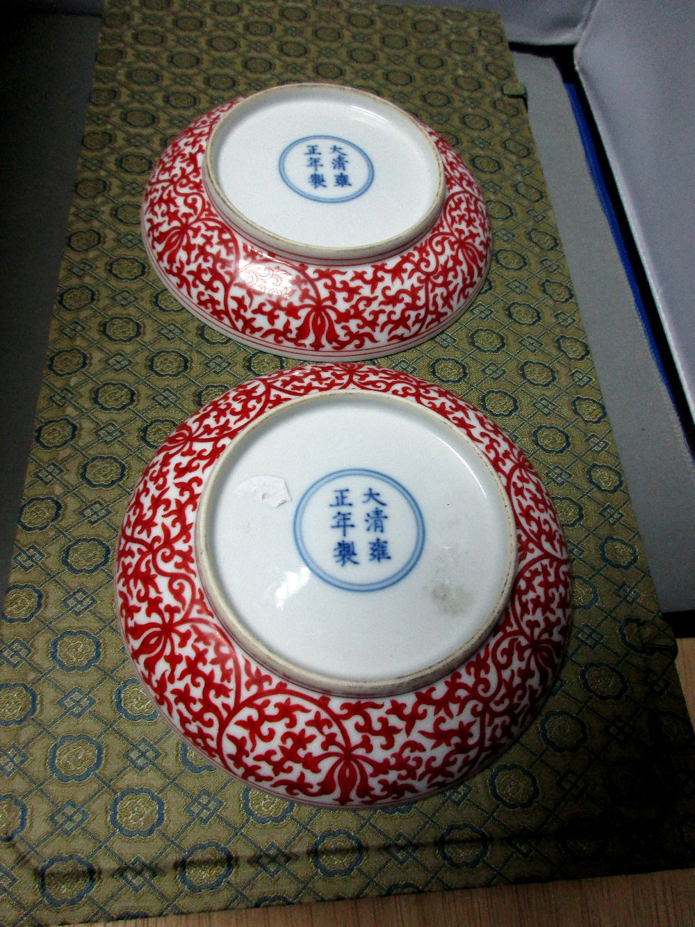 A brocade boxed pair of dishes, six character marks of Yongzheng, the exteriors with iron red