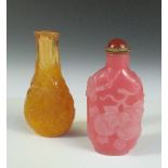 Two moulded glass snuff bottles and a stopper, the flattened bottle shape of the amber example