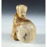 A late 19th/early 20th century marine ivory netsuke stained and carved as a boy standing over a