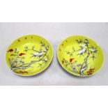 A pair of yellow ground saucers painted in grey with peaches, the heads of the millet and three