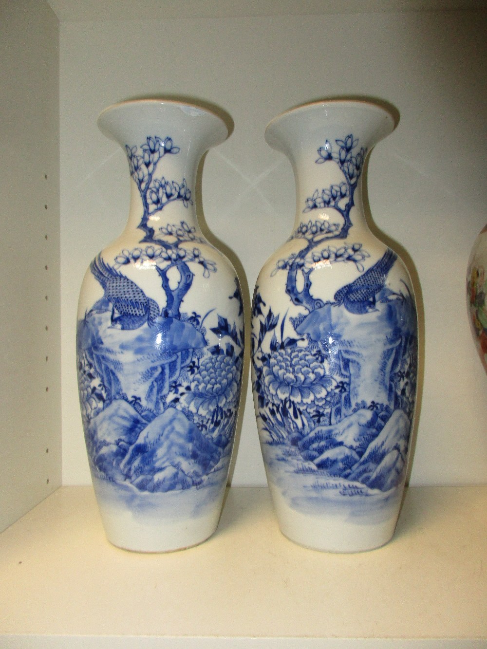 A pair of late 19th/early 20th century blue and white vases, magnolia flowering on the waisted