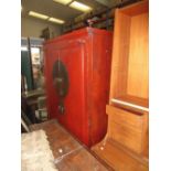 A red lacquer marriage cabinet, the doors with a large circular brass lock plate above the handles