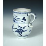 An early 18th century underglaze blue and red mug, a blue scroll band painted on the rim above three