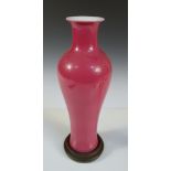 A pink monochrome baluster vase with wood stand, the evenly glazed slender shape with blue six