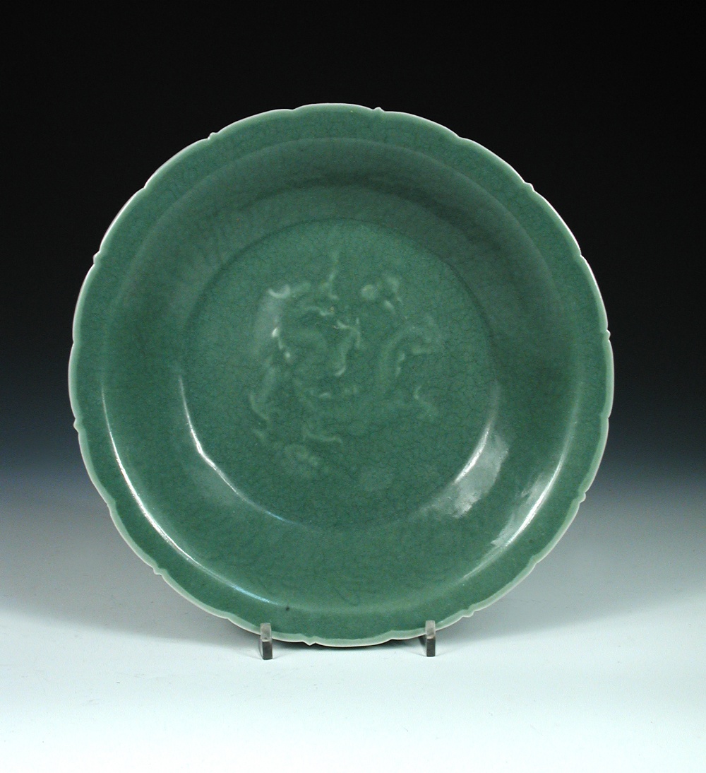 A Yuan celadon dish, the barbed rim enclosing incised foliage on the cavetto and a central dragon