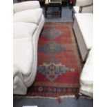 A Turkish red ground rug, (worn) 221cm x 157cm