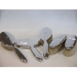 Four silver backed brushes and a silver backed mirror