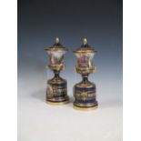 A pair of early 20th century Vienna porcelain urn vases on pedestals decorated with classical scenes