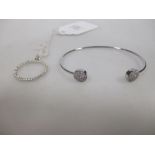 A small diamond set open bangle, each open end set with a disc pave set with small diamonds,