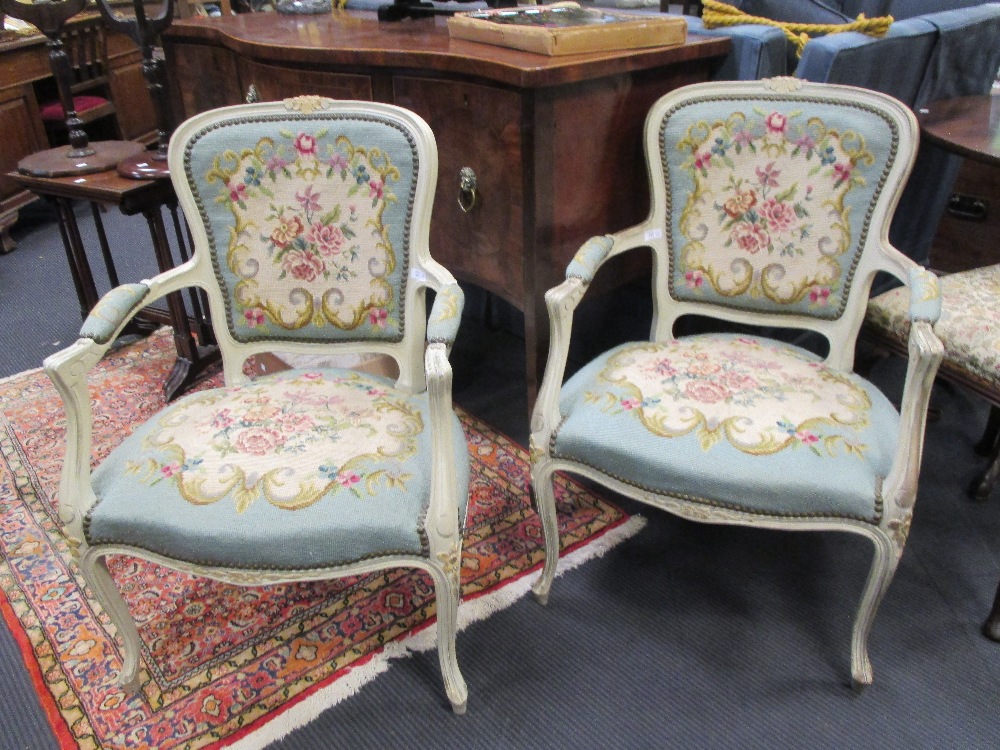 A pair of cream painted needlepoint upholstered open armchairs