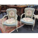 A pair of cream painted needlepoint upholstered open armchairs