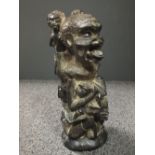 A mid 20th century African carved hardwood figure of a man with plate in his hip and small